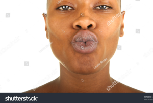Woman puckering lips with dark pigmentation.