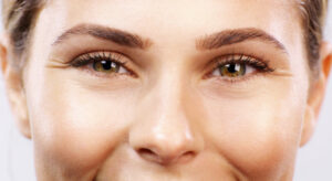 Eyes, face and beauty with a woman model in studio for health, skincare and wellness. Cosmetic, healthy and antiaging with a closeup of a young female looking radiant, glowing or perfect with a smile | Look Natural Micropigmentation Clinic Woman’s eyebrows after professional micropigmentation treatment.