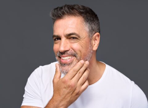 Middle-aged man smiling and touching his beard.