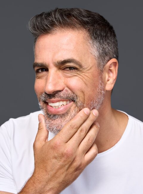 Middle-aged man smiling and touching his beard.