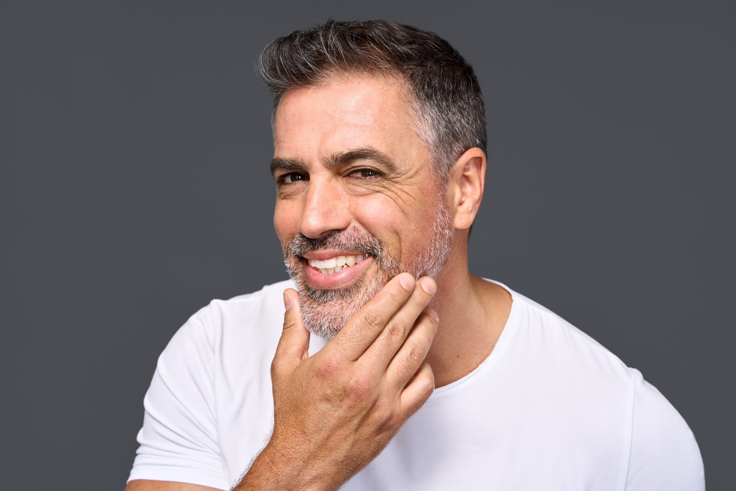 Middle-aged man smiling and touching his beard.